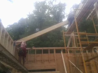 Carpenter raising a rafter beam on a new second story frame in Kansas