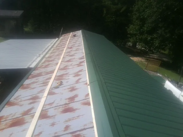 Old rusted panels beside newly installed green metal roofing — Wind Damage Roof Repair by Roofing Brothers in Kansas