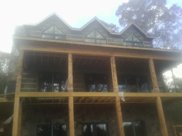 Dormers and porch framing on a large log home under construction — Roof Coating work by our crew in Kansas