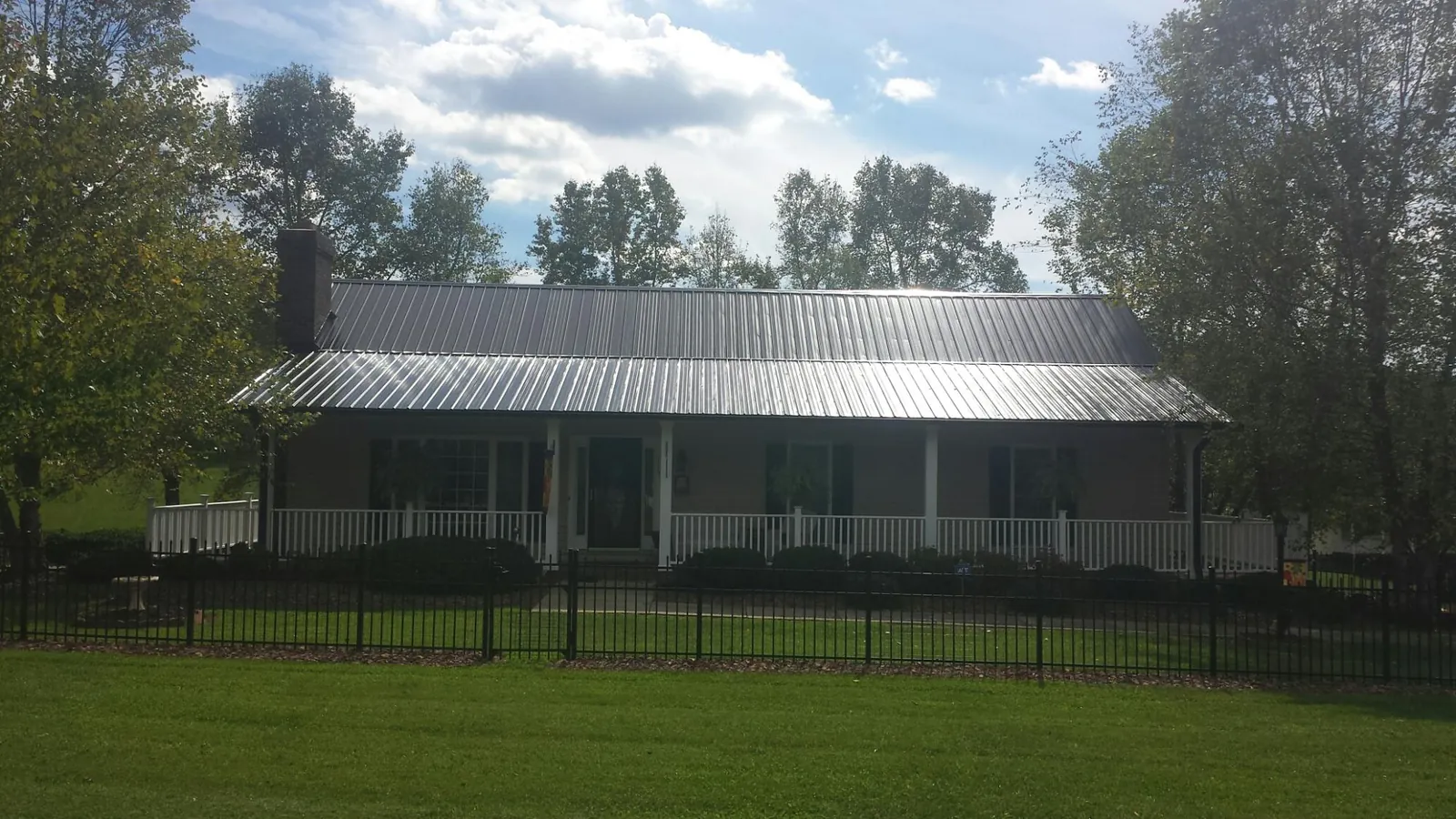 Gray metal roof on a brick ranch with a full width front porch — Gutter Guard Installation work by our crew in Kansas