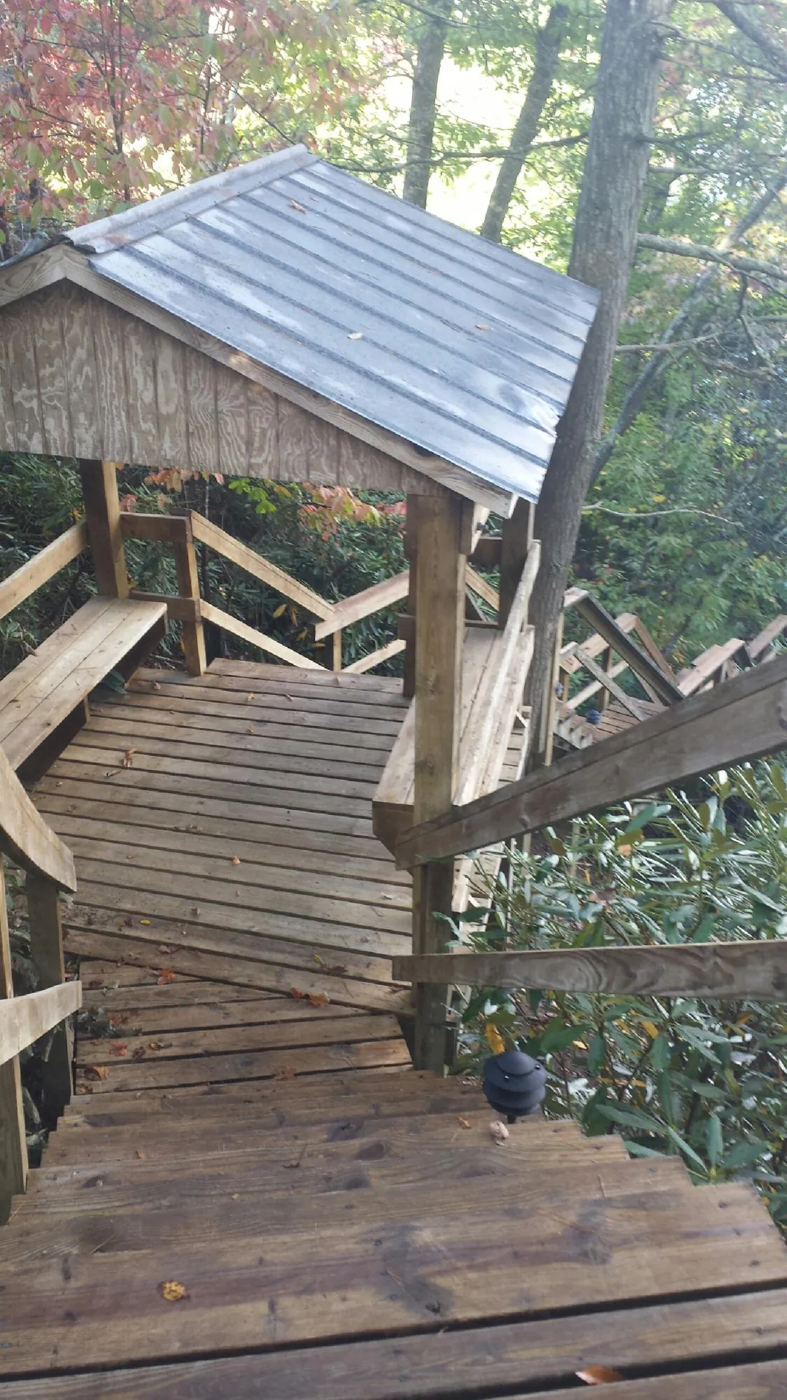 Metal roofed shelter over wooden steps on a wooded walkway — Skylight Repair & Installation work by our crew in Kansas