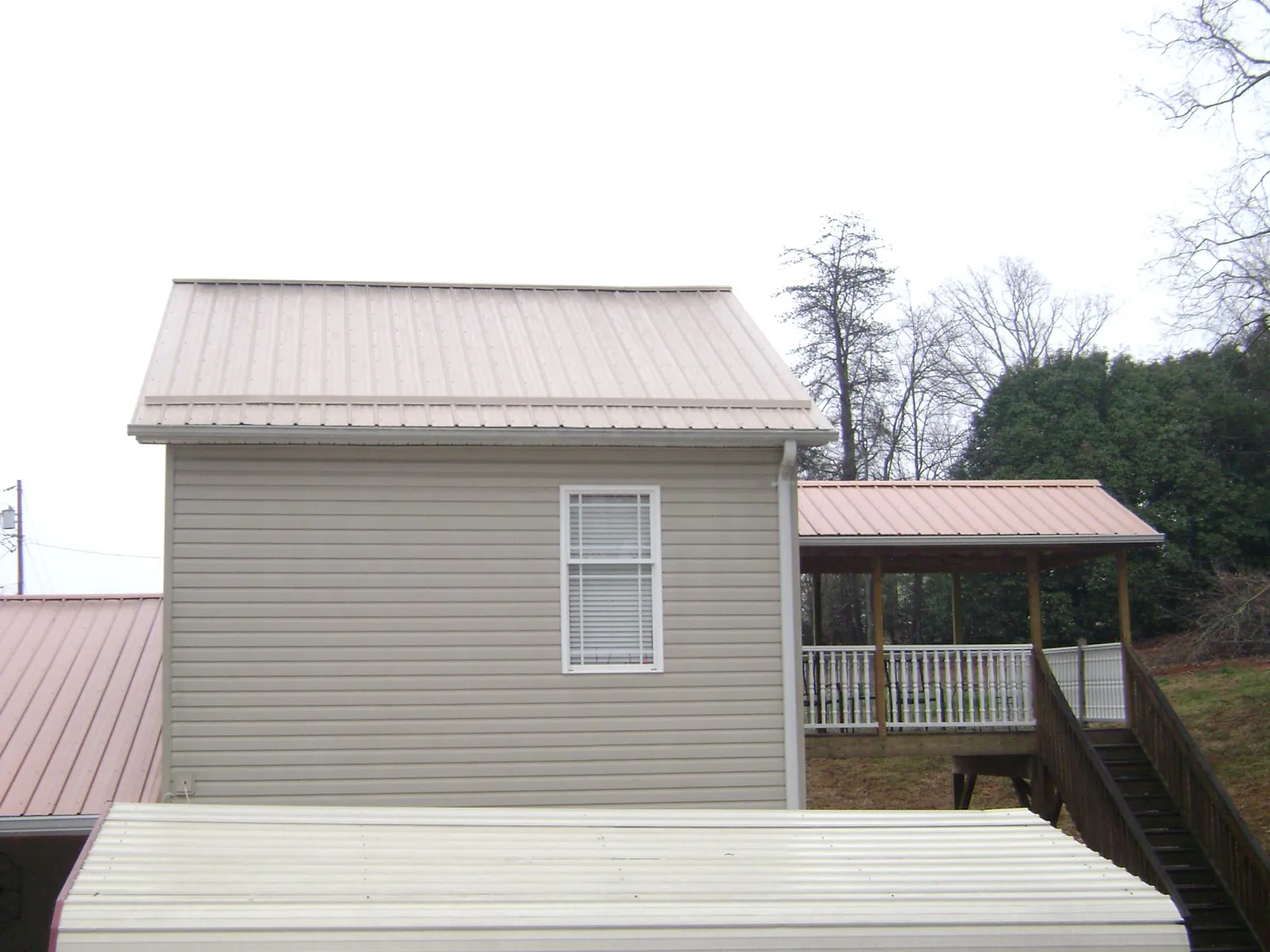 Tan metal roofs on a two story addition and attached porch, from a Roof Replacement job in Kansas