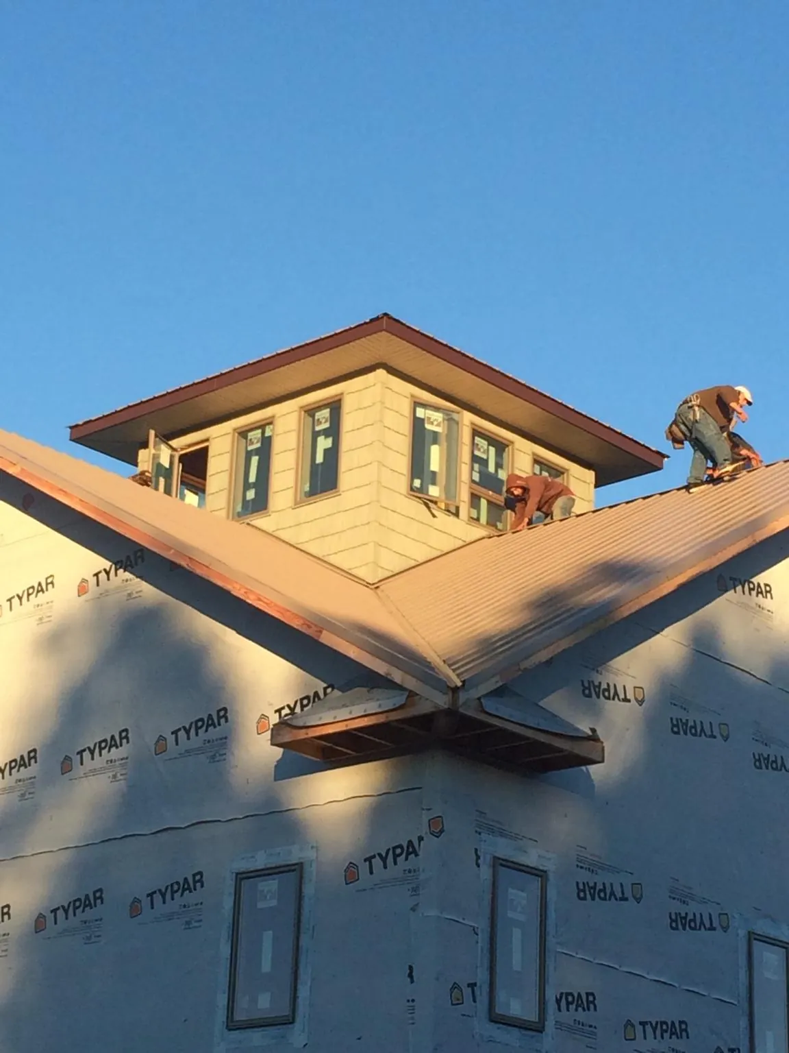 Roofers working around a rooftop cupola on a new metal roof at sunset — Roof Waterproofing in Kansas by Roofing Brothers